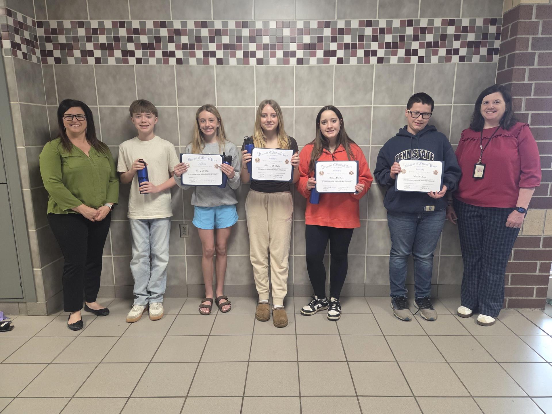 7th Grade students proudly holding their certificates for winning an essay contest.
