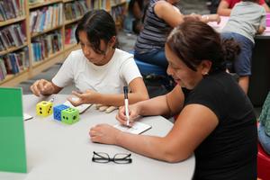 girl and mom playing a dice game in school library