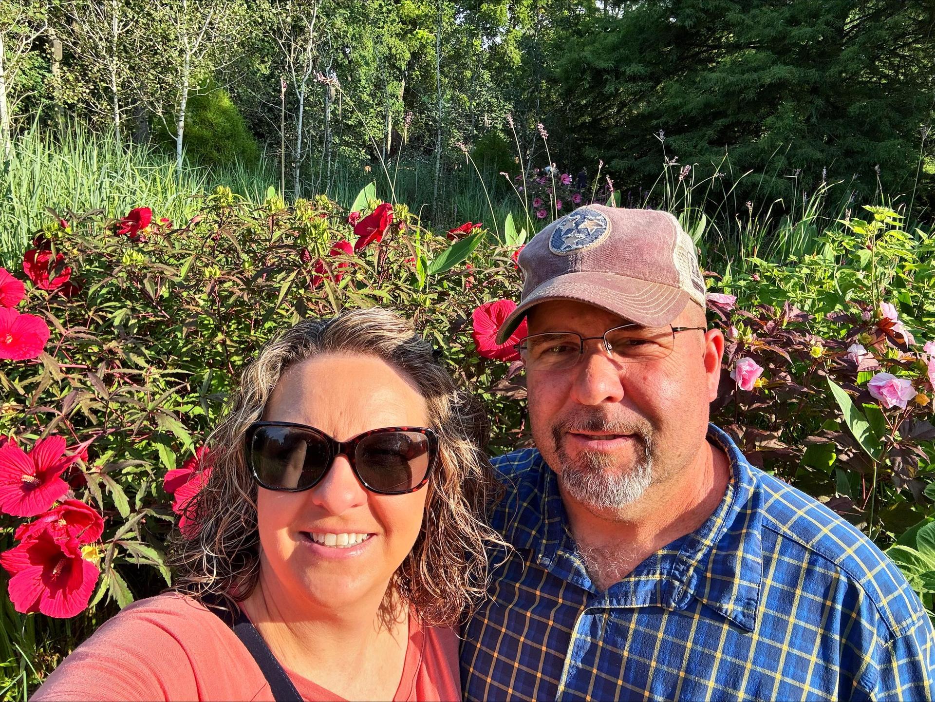 Man and woman in front of flowers. 
