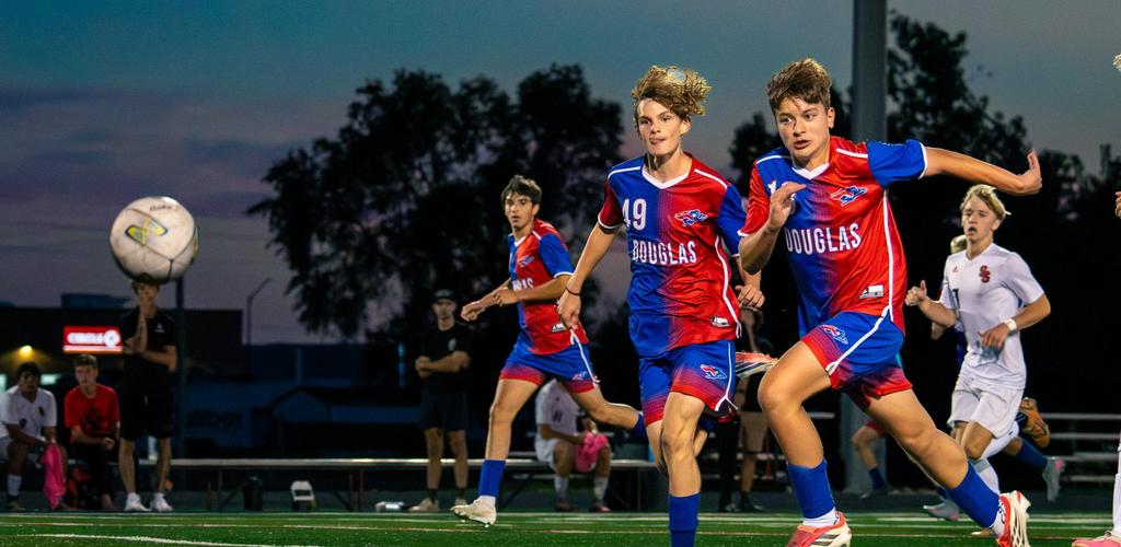 Douglas varsity soccer homecoming players in action during a game at dusk.