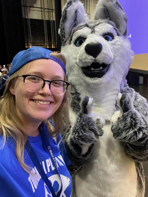 picture of a smiling women with glasses and the husky mascot.