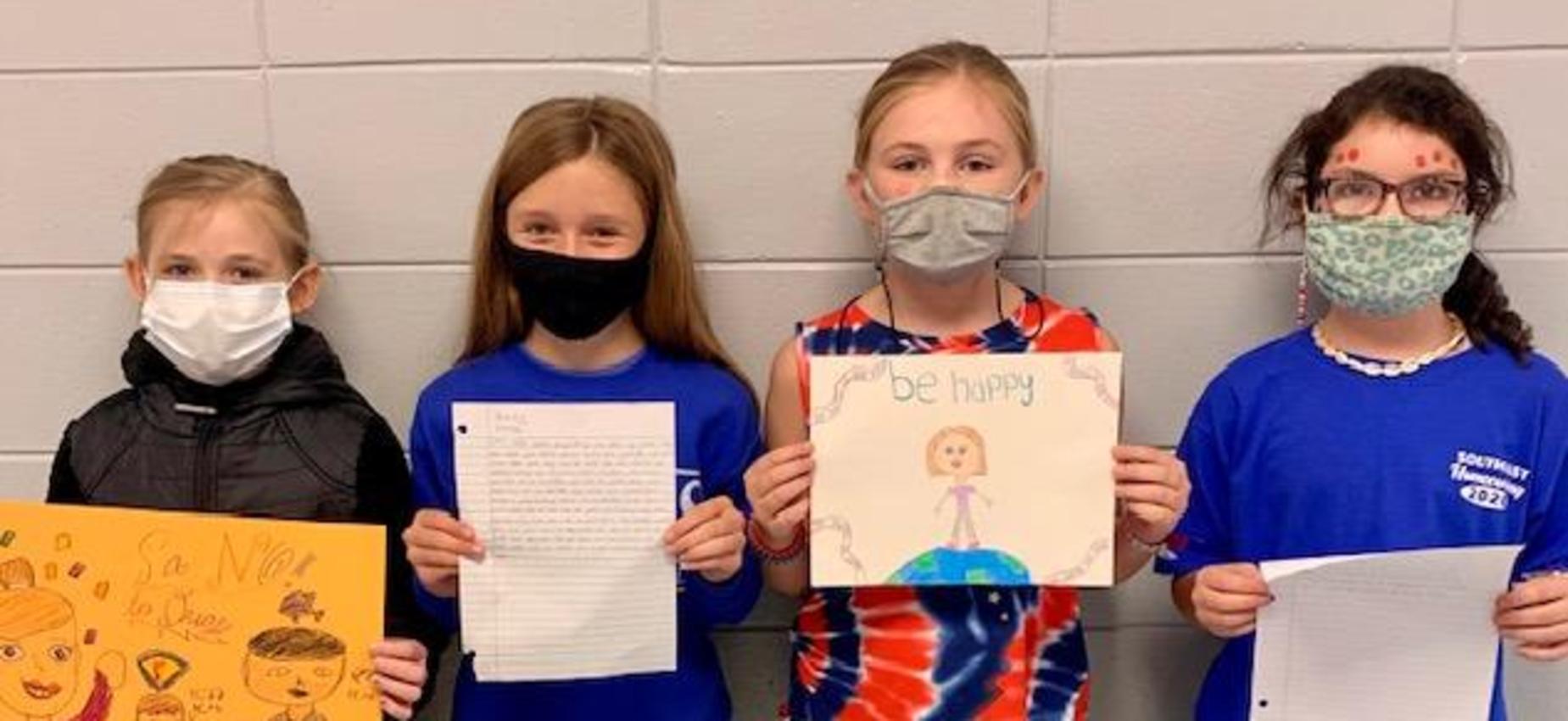 4 girls holding their winning posters and essays