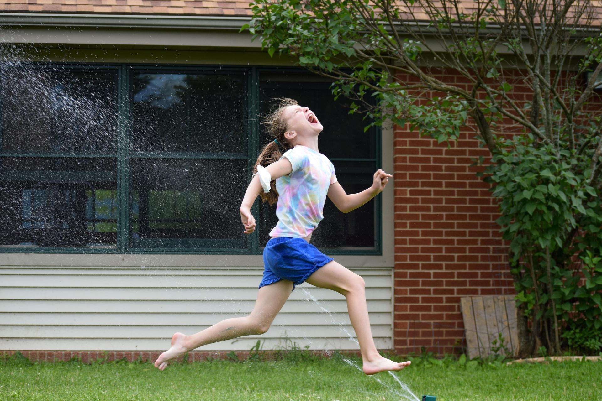 Child running through sprinkler