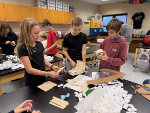 students gathered around table filled with supplies building a nest