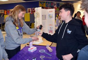 a boy testing his grip strength on a device held by a girl