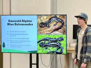 A student speaks in front of a smart TV with a slide about a salamander