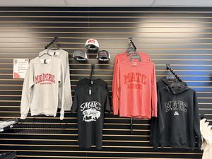 Clothing items including sweatshirts and caps displayed on a rack.
