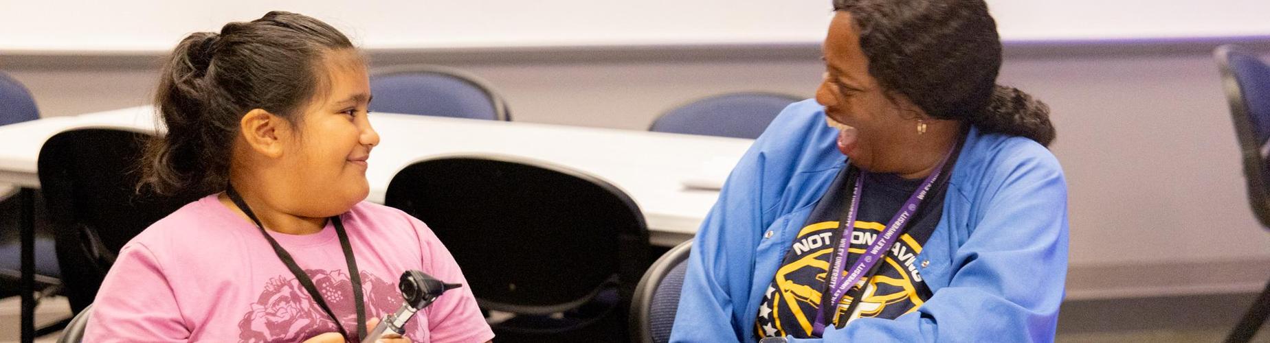 A child and an adult laughing and enjoying a conversation in a classroom setting.