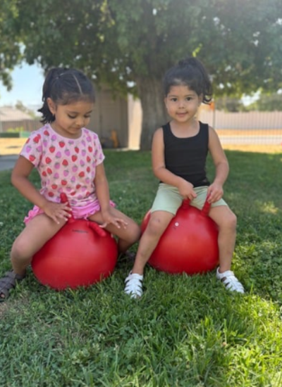 Two students sitting on red bouncy balls