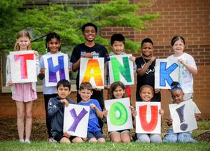 Kids holding up signs that say thank you.