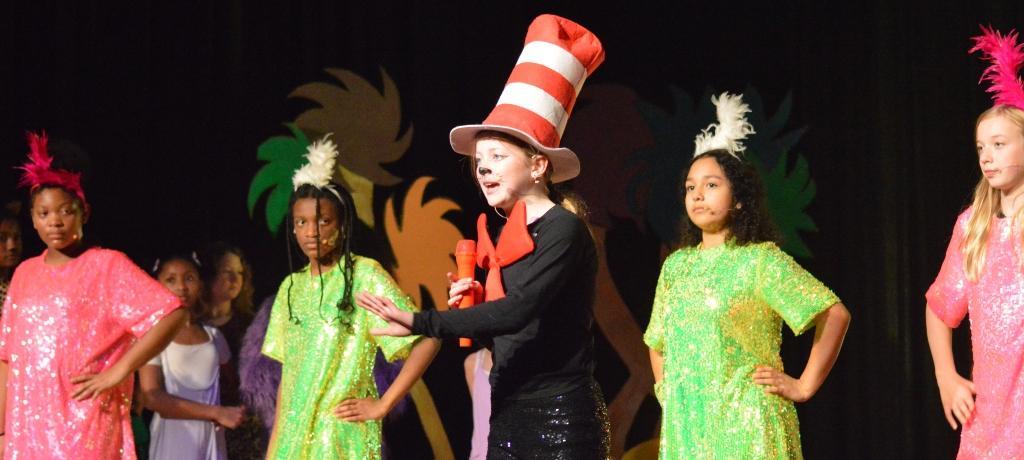 student costumed as Cat in the Hat sings on stage