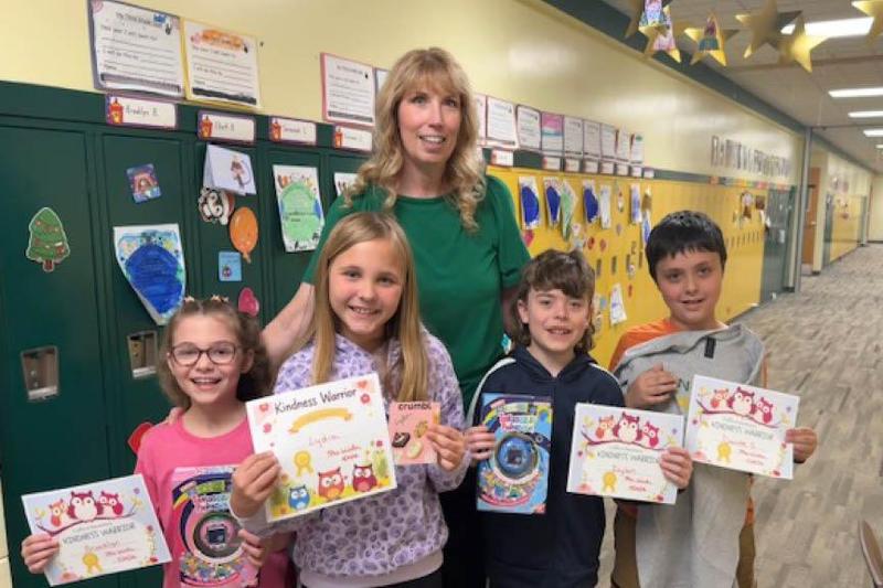 Brooklyn Bianca, Lydia Mellon, Dylan Dukic, and Dante Scarpine hold their kindness certificates along with the raffle prizes they earned; Mrs. Winter is also pictured