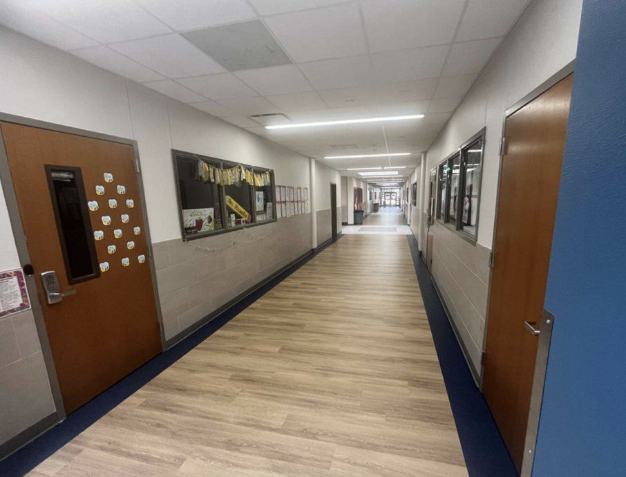 Bright indoor hallway featuring doors and bulletin boards.