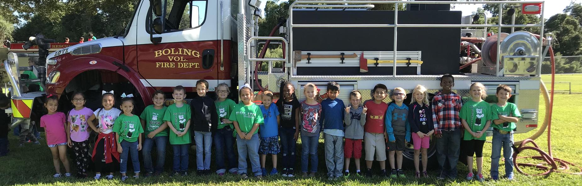 school children lined up in front of a fire truck