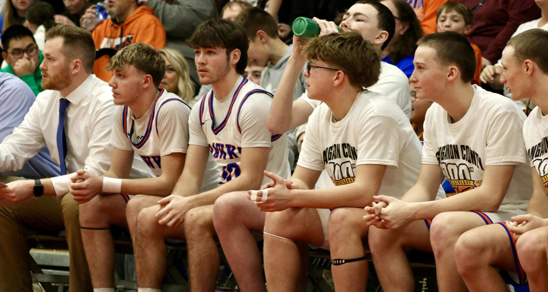 A group of male basketball players sitting on a bench during a game.