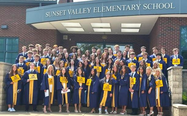 students lined up on front steps in graduation regalia