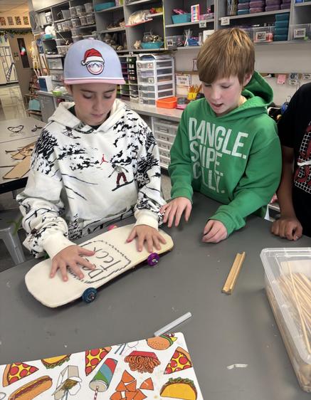 Two children working together on a skateboard project at a table.