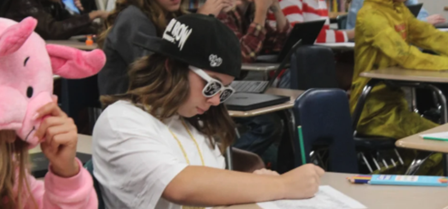 Students seated in class working on a worksheet in costume