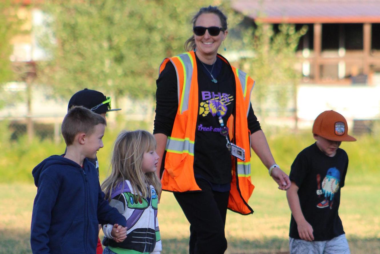 A teacher walks outdoors with students.