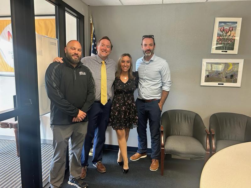 4 adults standingn in a conference room