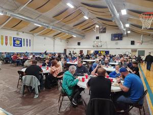 Historic gym filled with tables and people eating.