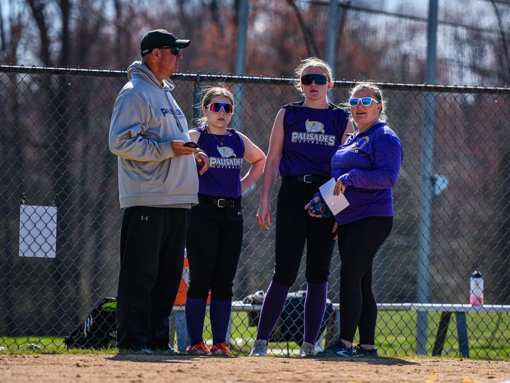 Coaches and athletes having a discussion on the softball field.