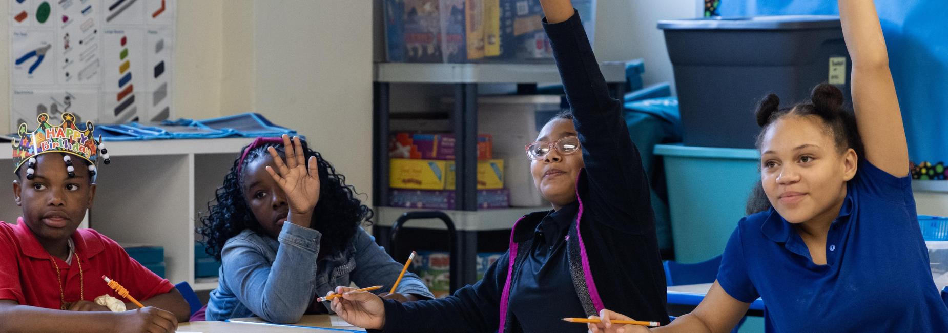 Elementary students raise their hands