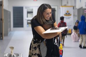 An elementary teacher smiles and gives a hug to a student