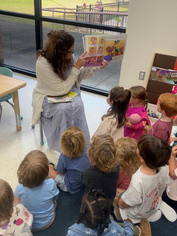 A woman reads to a group of children sitting on the floor.