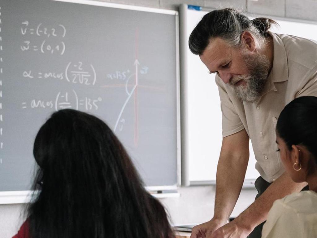 A teacher explaining math concepts to students at a chalkboard.
