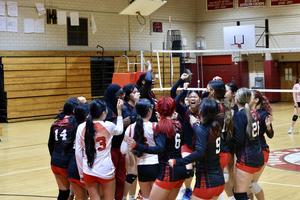 Girls' Varsity Volleyball team gathered together cheering.