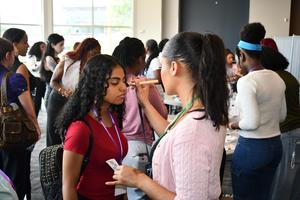 A woman applies makeup to a student's face