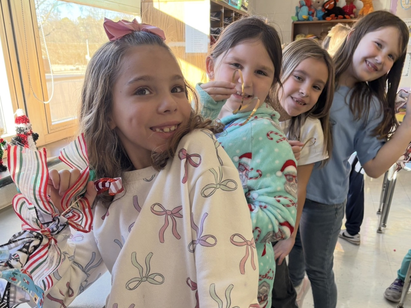 Smiling children pose together while making crafts in a classroom.
