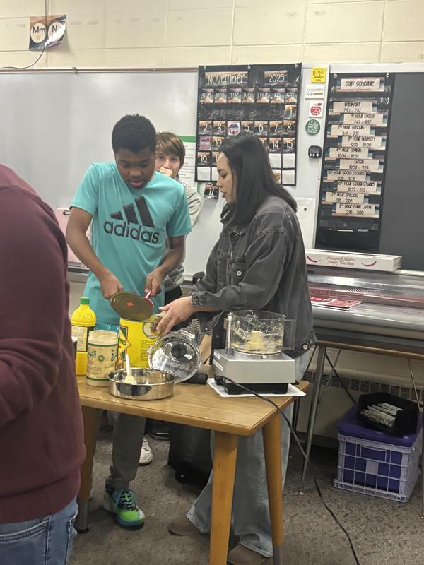 Two students collaboratively measure ingredients for a recipe at the cooking station.