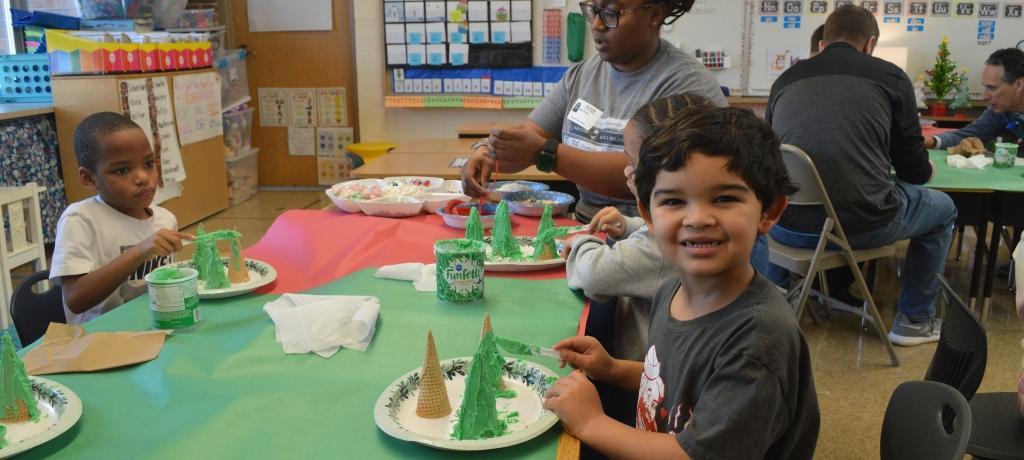 boy smiles for the camera while applying green frosting to ice cream cone