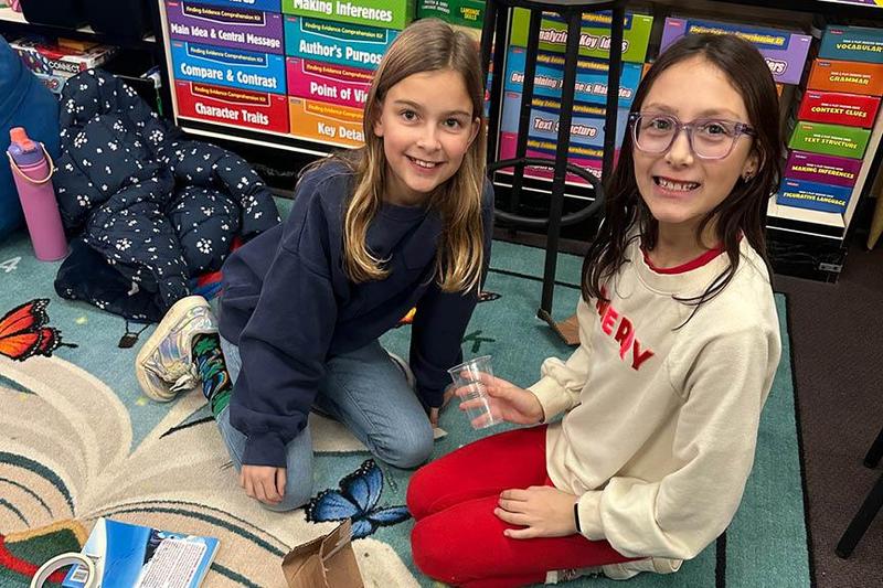Fourth-graders Adeline Smorul and Azalea Llerena create an elf zipline during the book fair