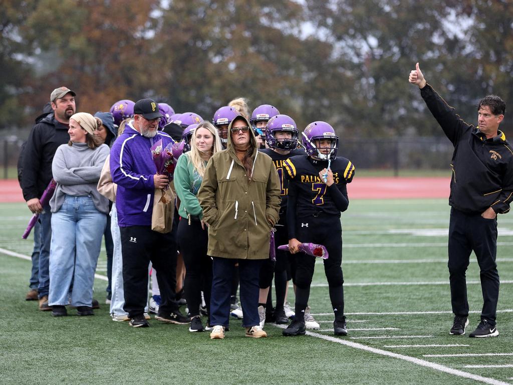 Parents of football players with their children standing in the rain on the football field.