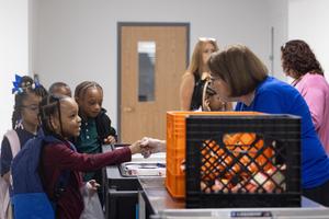 A cafeteria worker shakes the hand of a first grader