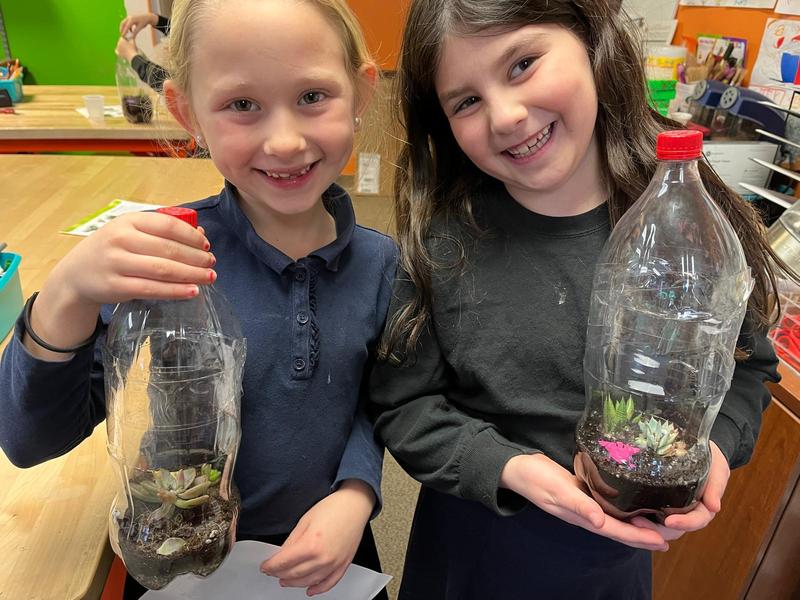 Two second graders showing their terrariums.