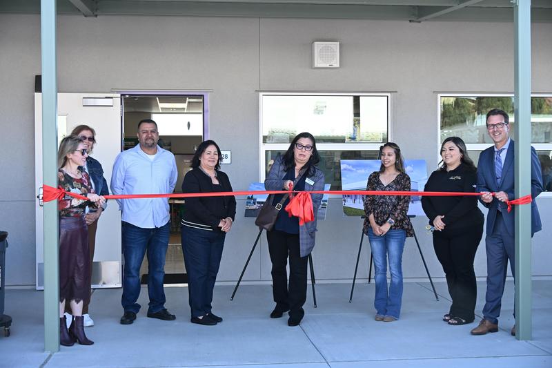 Eight people standing behind a red ribbon