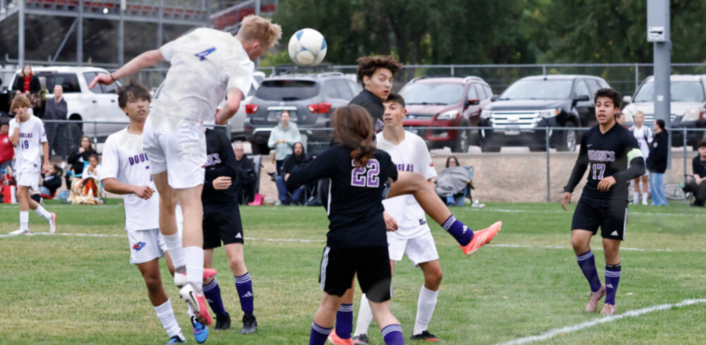 Players jump for a soccer ball in an outdoor match.