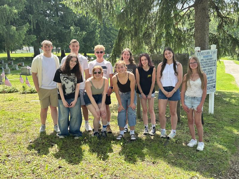 students standing in cemetery smiling at camera