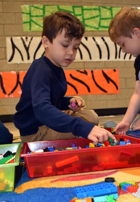 A boy sorting colorful building blocks on a play mat.
