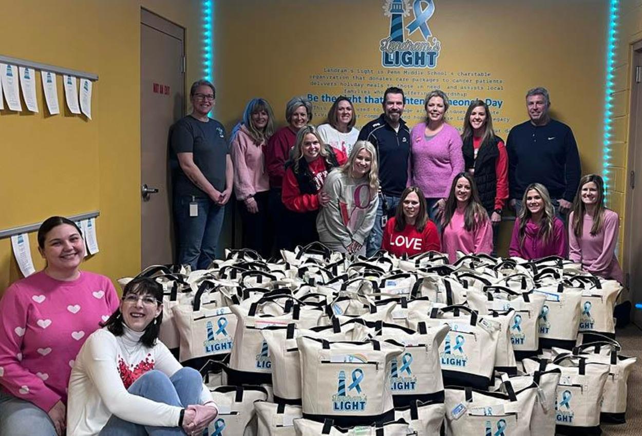 Penn Middle staff pose with the 125 totes that they packed for cancer patients on behalf of Landram's Light foundation