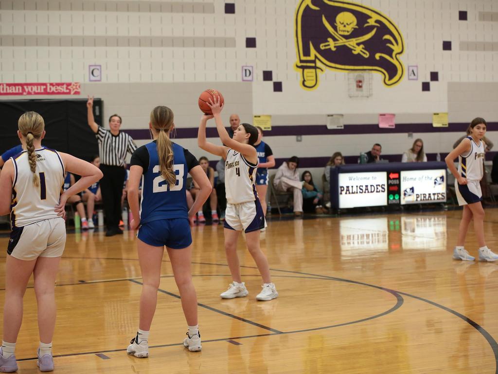 A student basketball player shooting a basket in the indoor court during a game.
