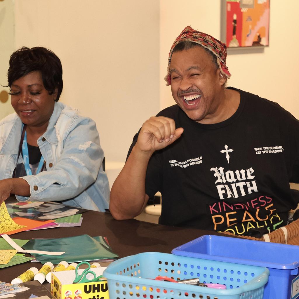 Two people smiling and making art