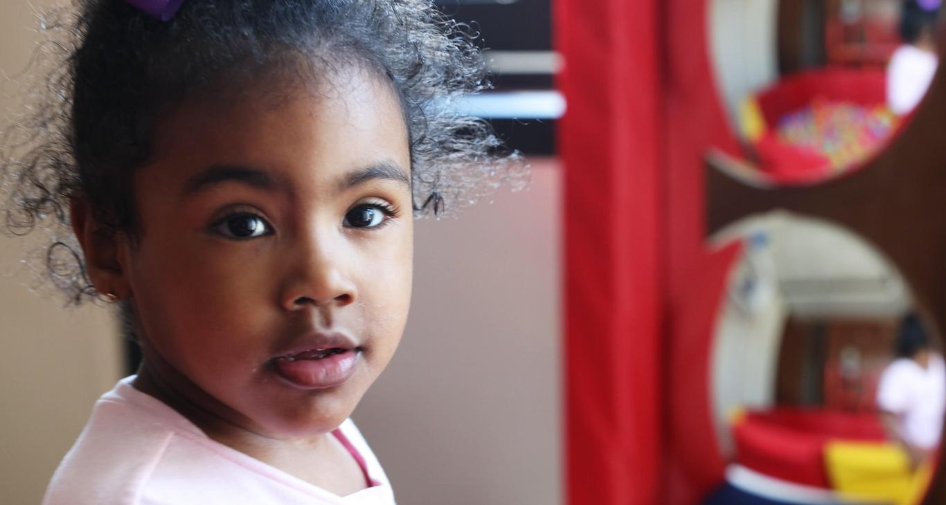A young child with curly hair in a playful environment.