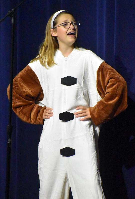 Girl in a costume resembling a character, singing on stage.