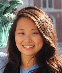 Smiling woman with long hair standing in front of a green sculpture.