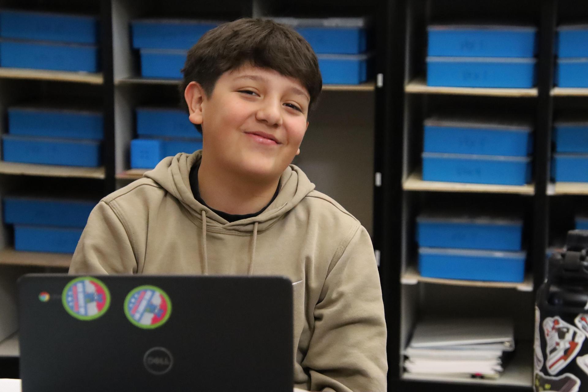 middle school boy smiling at camera in the classroom